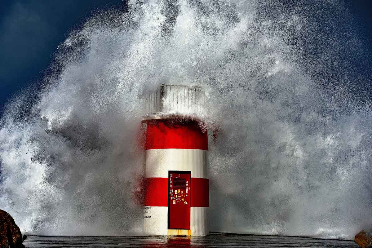Waves crash over a lighthouse at Nazare - One of the 10 best day trips from Libon
